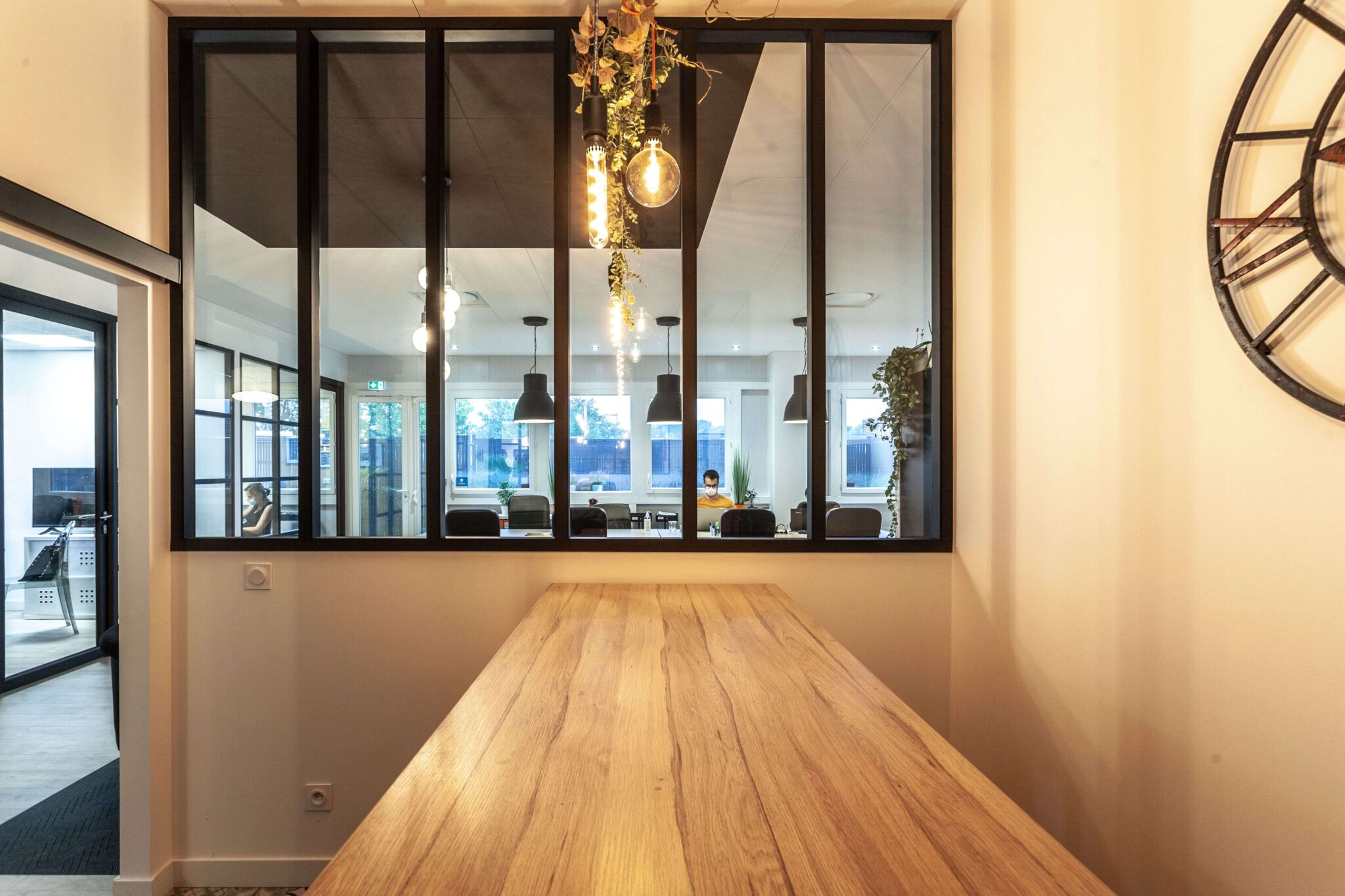Salle de restauration en bois avec vue depuis la verrière sur la salle de réunion centrale